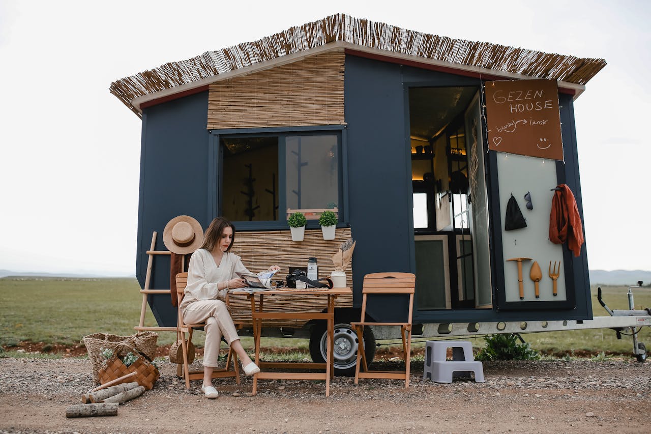 Woman sitting outside a boho-style mobile home, enjoying tranquility.