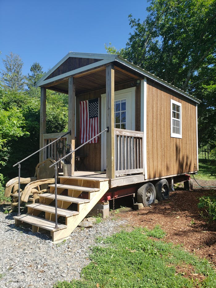 A cozy wooden tiny house with an American flag, perfect for small living enthusiasts.